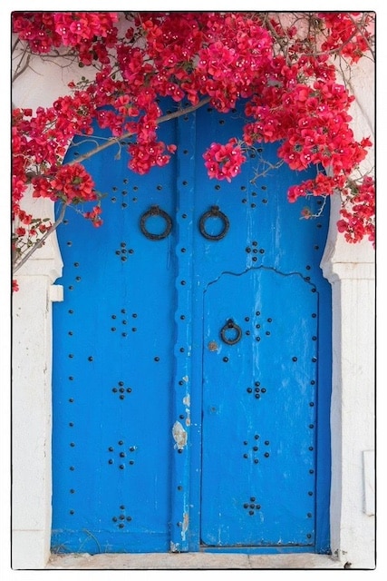 Puerta de entrada en color azul con buganvilla